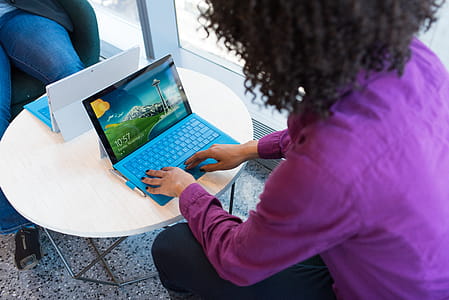 Person Using Blue Laptop Sitting Beside Table thumbnail