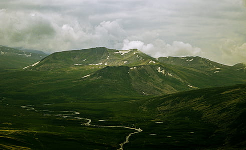 river surrounded by mountain range under gray sky thumbnail