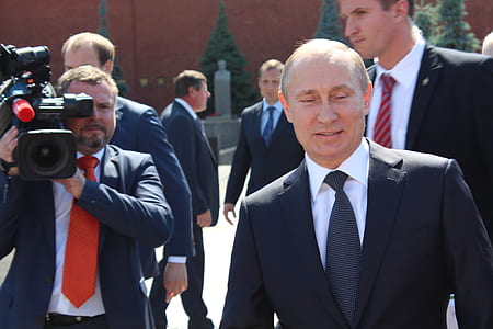 man wearing black notched lapel suit near man holding video camera thumbnail