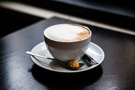 cup of latte on saucer with gray spoon thumbnail