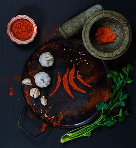 round steel plate with red powder and two garlic heads on top thumbnail
