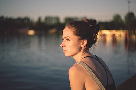 woman sitting on bridge near body of water during daytime thumbnail