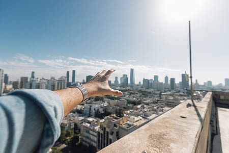 person in denim long-sleeved top while near cliff building thumbnail