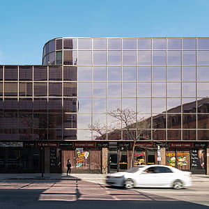 white sedan near brown building facade thumbnail
