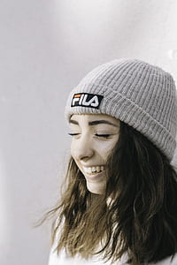 woman wearing gray Fila knit cap and white shirt thumbnail