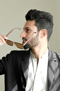 Man Holding Brown Framed Sunglasses With Black Suit thumbnail