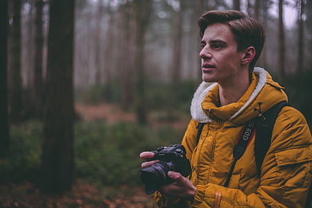man wearing yellow jacket holding DSLR camera thumbnail