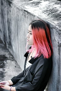 woman sitting and leaning on gray and black concrete wall outdoor during daytime thumbnail