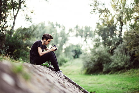 man browsing camera while sitting on the cliff thumbnail