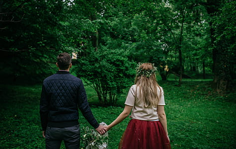couple holding hands walking on grass at daytime thumbnail