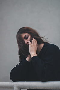 woman in black scoop-neck long-sleeved shirt near gray wall thumbnail