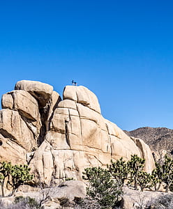 two person standing on rock formation under blue sky during daytime thumbnail