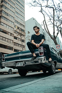 man sitting on green coupe at daytime thumbnail