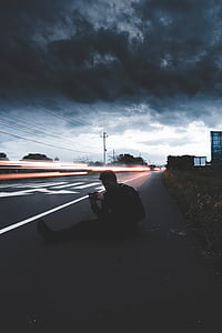 man sitting beside road thumbnail
