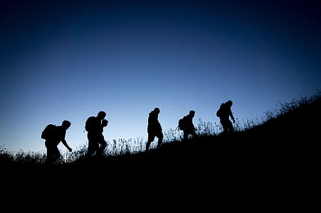 silhouette of people climbing on mountain during nighttime thumbnail