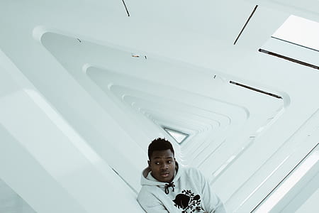 man wearing pullover hoodie leaning on white wall thumbnail