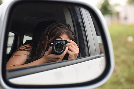 reflection of woman taking photo on vehicle side mirror thumbnail