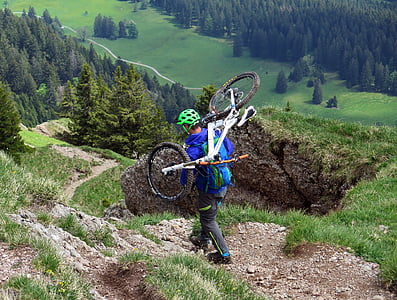 man carrying his bicycle while walking on mountain thumbnail