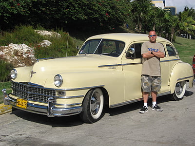 man standing beside parked beige car thumbnail