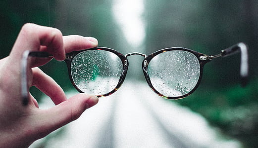 person holding eyeglasses with moist thumbnail