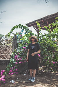 Woman Wearing Black Crew-neck Dress Standing Beside Pink Flowers thumbnail