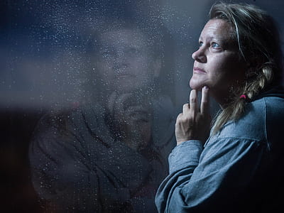 woman standing in front of glass thinking while holding chin thumbnail