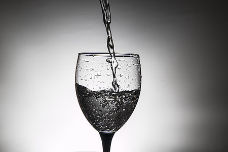 pouring water on wine glass grayscale photography thumbnail