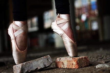 selective focus photography of ballerina stand on concrete bricks thumbnail