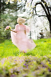 woman in pink chiffon dress holding pink of flower bouquet running at daytime thumbnail