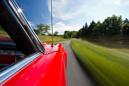 time lapse photo of classic red car running on concrete road thumbnail