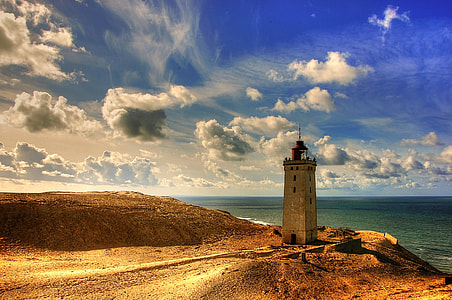 in distant photo of lighthouse near calm body of water thumbnail