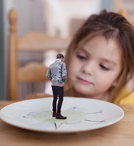 man wearing blue denim jacket standing on round white ceramic saucer thumbnail