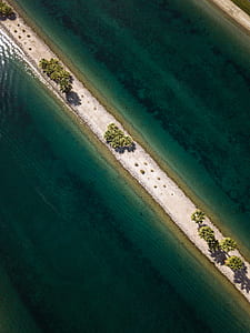 aerial view of narrow road with green plant in between body of water thumbnail