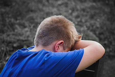 boy wearing blue shirt leaning on grey wooden chair thumbnail