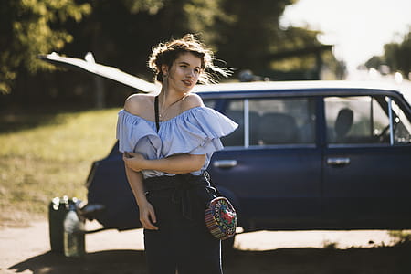 Woman in Blue Blouse Standing Near Blue Station Wagon thumbnail