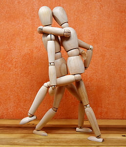 two brown wooden dancing mannequins beside orange painted wall thumbnail