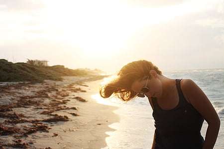 woman wearing sleeveless top on seashore under gray clouds thumbnail