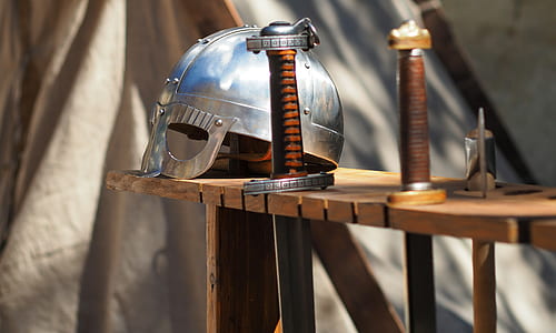 selective focus photography of knight helmet beside sword thumbnail