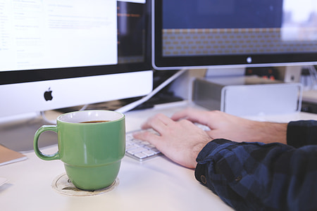 green ceramic mug on top of white coaster near person hand holding Apple Keyboard thumbnail
