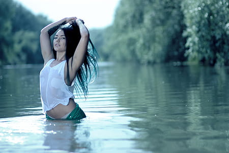woman standing in body of water near trees thumbnail