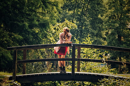 man in pink cardigan standing on brown wooden bridge thumbnail