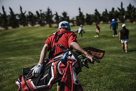 Man Walking Carrying Black and Red Golf Bag on Green Grass Field thumbnail