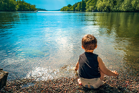 boy in black tank top sitting on sea shore thumbnail
