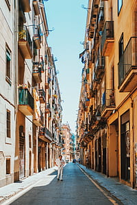 man wearing white shirt and white pants standing between beige concrete houses at daytime thumbnail