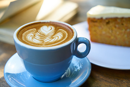 close-up photo of cappuccino in blue ceramic mug and saucer beside cake thumbnail