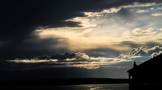 silhouette photo of black house beside body of water thumbnail