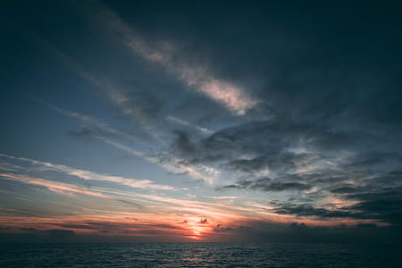 ocean water under blue sky and white clouds during golden hour view thumbnail