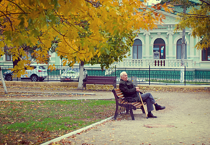 man sitting on brown wooden bench with cast-iron frame thumbnail