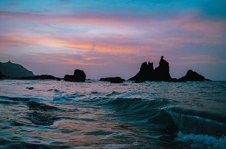 rock formation on body of water during golden hour thumbnail