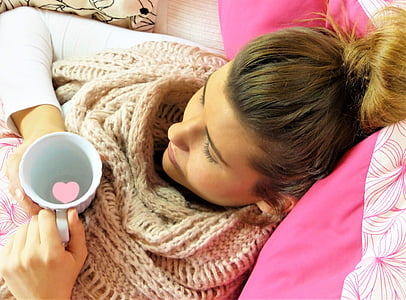blonde haired woman holding cup while lying on bed thumbnail